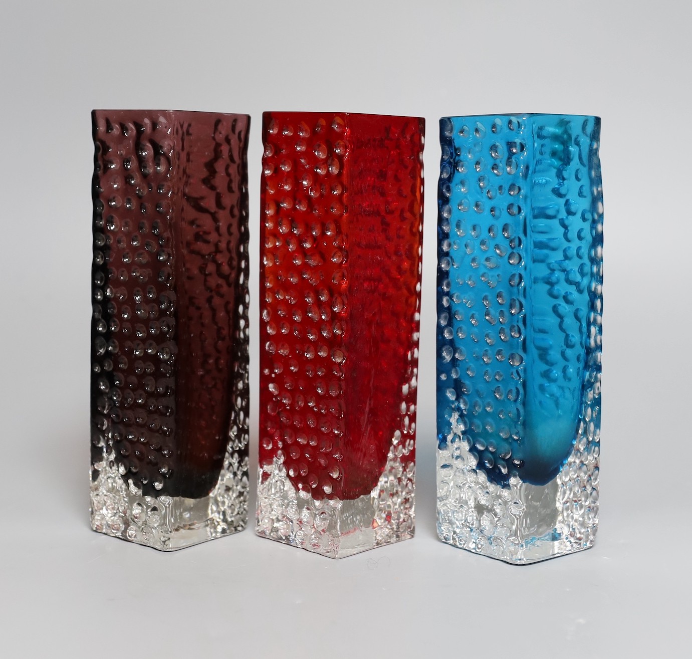 A trio of Whitefriars 'Nailhead' vases, designed by Geoffrey Baxter, kingfisher blue, red and amethyst glass, 20 cms high